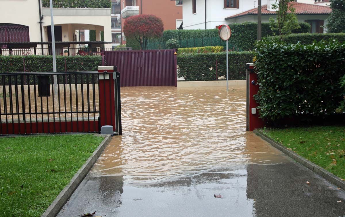 überschwemmte Straße und Toreinfahrt zu Grundstück mit leichtem Gefälle
