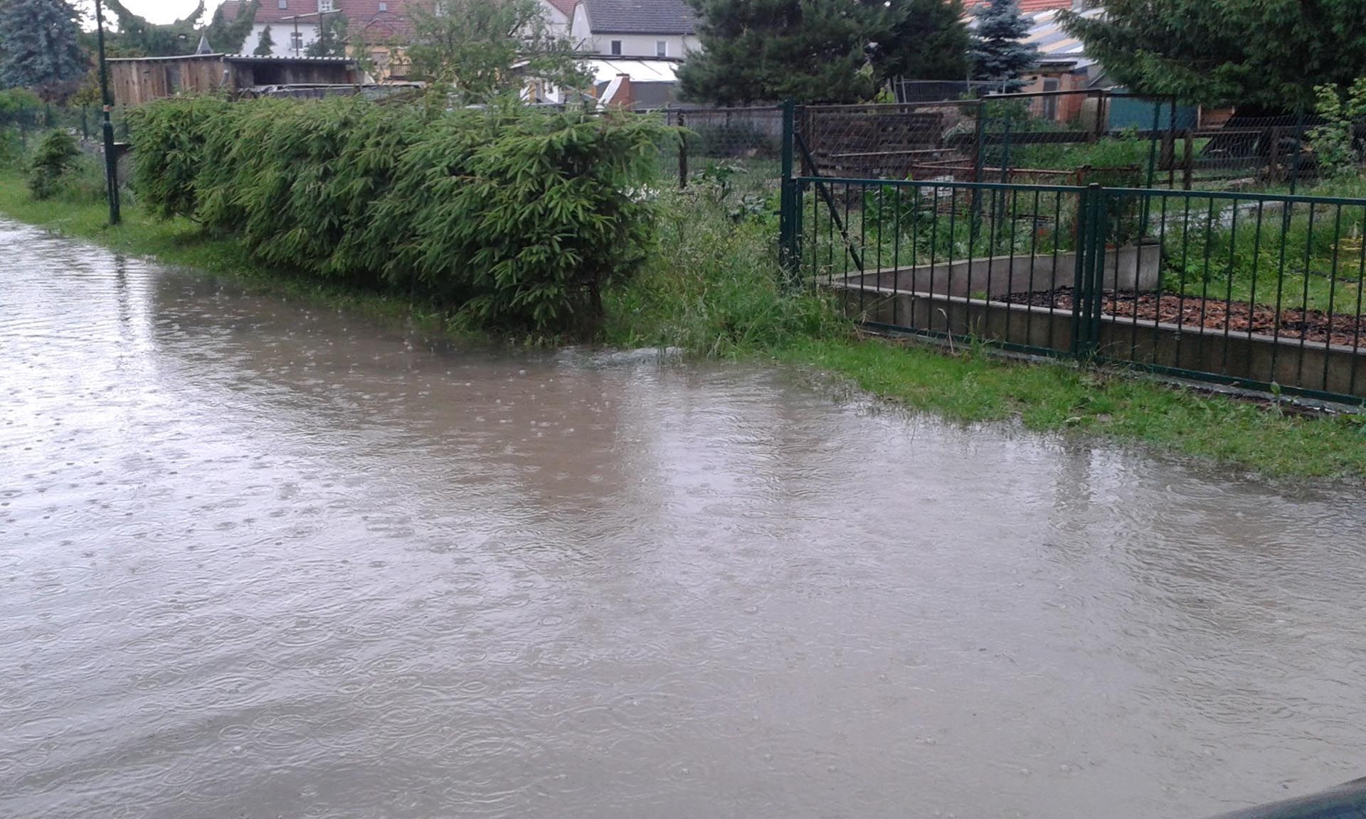 überflutete Straße mit Grundstück im Hintergrund