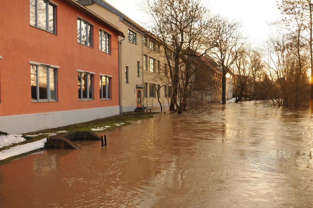 überschwemmte Straße mit Häuserreihe an der linken Seite