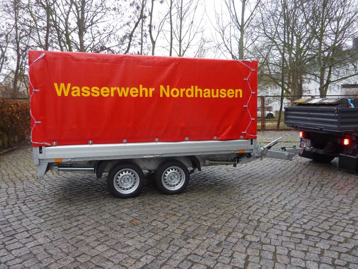 geschlossener Hochwasserschutzanhänger mit Aufschrift "Wasserwehr Nordhausen" auf roter Plane
